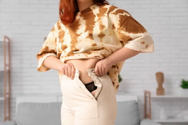 Image of woman trying to do her trousers up after pregnancy weight gain Newcastle