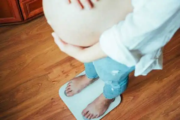 Image of woman weighing herself and experiencing weight gain through pregnancy Newcastle